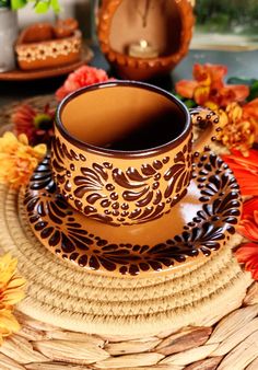 a cup and saucer sitting on top of a woven place mat next to flowers