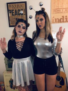 two women dressed in costumes standing next to each other and posing for the camera with their hands up