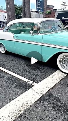 an old blue and white car parked in a parking lot