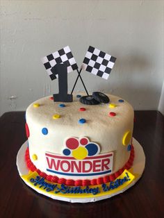 a birthday cake with the number one on it and race flags sticking out of it