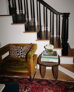 a living room with two chairs and a coffee table in front of a stair case