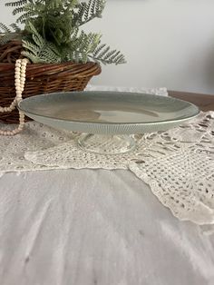 a glass plate sitting on top of a table next to a basket filled with flowers