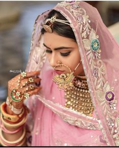 a woman in a pink outfit with jewelry on her hands