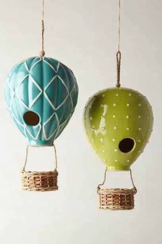 two hot air balloons are hanging from twine strings with holes in the middle one is green and the other is blue