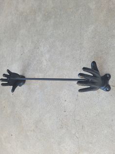 a pair of black gloves on top of a white floor next to a metal pole