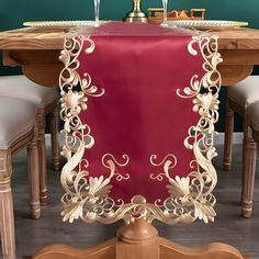 a red table cloth on top of a wooden table with two white chairs and a wine glass holder