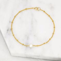 LILY & ROO's delicate handmade single pearl bracelet in gold. This classic yet contemporary single pearl bracelet is made from 14ct gold filled satellite chain and a beautiful single freshwater seed pearl. A stunning jewellery gift for her that goes with any outfit. All single pearl bracelets on satellite chain come in a luxury LILY & ROO box. Gold Filled means a layer of pure gold pressure-bonded to the core metal. Gold filled items are 5 to 10 times thicker than gold plating. Give your jewellery a little TLC to keep your jewellery shining bright. Your stunning pearl bracelet will be sent to you in a complimentary Lily & Roo gift box with ribbon tied in a beautiful bow. Minimalist Gold Pearl Bracelet With Delicate Chain, Dainty Gold Pearl Bracelet With Pearl Charm, Dainty Yellow Gold Pearl Beaded Bracelets, Dainty Yellow Gold Beaded Bracelets With Pearl Charm, Gold Pearl Bracelet With Delicate Chain, Minimalist 14k Gold Filled Beaded Bracelets With Pearl Charm, Minimalist Pearl Chain Bracelet, Minimalist Gold Pearl Chain Bracelet, Gold Minimalist Pearl Chain Bracelet