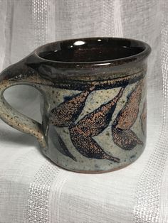 a brown and white coffee cup sitting on top of a tablecloth covered table cloth