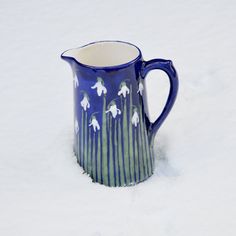 a blue and white pitcher sitting in the snow