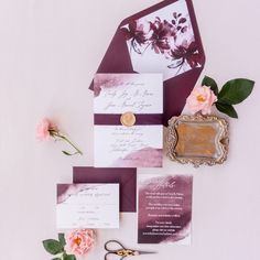 the wedding stationery is laid out on top of each other, with flowers and scissors