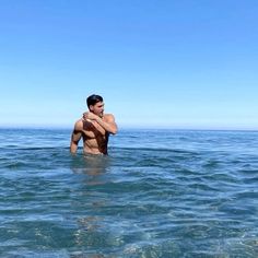 a man standing in the ocean with his arms crossed