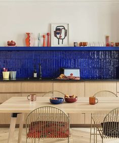 a kitchen with blue tile backsplashing and wooden dining table surrounded by chairs