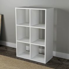 a white shelf with four cubes sitting on top of it next to a rug