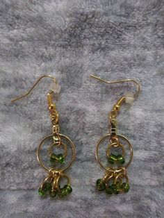 Green Dangle Hoop Earrings With Beaded Fringey Bottoms MATERIALS: -GREEN GLASS SEED BEADS -RUBBER EARRING BACKINGS -GOLD PLATED ALLOY METAL JUMP RINGS, EARRING WIRES AND HOOP EARRING FINDINGS Introducing our chic and trendy Green Dangle Hoop Earrings. These eye-catching earrings are designed to add a touch of elegance to any outfit. Made with high-quality materials, the hoops feature a stunning green color that is sure to complement any skin tone. The beaded fringey bottoms add a playful and sty Green Metal Beaded Earrings For Party, Green Metal Beaded Party Earrings, Green Dangle Hoop Earrings In Metal, Green Dangle Metal Hoop Earrings, Green Metal Dangle Hoop Earrings, Green Beaded Earrings With Round Metal Beads, Green Metal Beaded Earrings With Round Beads, Green Wire Wrapped Dangle Hoop Earrings, Green Wire-wrapped Dangle Hoop Earrings