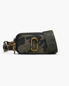 Straight from the Spring '16 runway to the bestseller list, now our forever icon. This version of our Snapshot is crafted in a specially designed camo jacquard, lined with a pop of color, and includes an exterior slip pocket for extra ease. Our signature J Marc hardware, a double zip compartment, and a removable and adjustable webbing strap make this crossbody bag big enough to hold what you need and small enough to carry anywhere. ​ | MARC JACOBS The Camo Jacquard Snapshot Bag in Camo Multi American Fashion Designers, Marc Jacobs Bag, Camo Print, Metallic Logo, Green Bag, Handbag Accessories, Wallet Case, Camera Bag, Bags Women