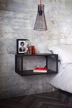 a bed with white sheets and pillows next to a wall mounted shelf that has pictures on it