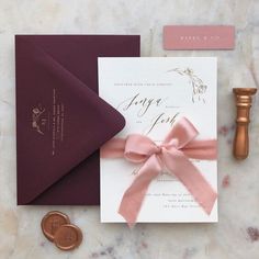 the wedding stationery is laid out on a marble table with a wax stamp and envelope