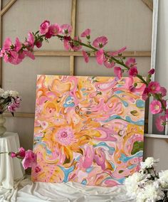 a painting is displayed on a table with flowers