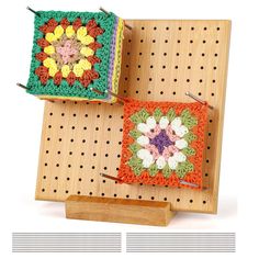 two small crocheted squares are sitting on a peg board