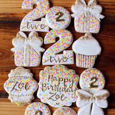 decorated cookies with numbers and bows are arranged on a wooden table in the shape of birthday cakes