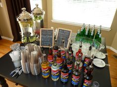 there are many bottles on the table with drinks in front of them and two silver shakers next to each other