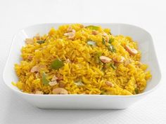 a white bowl filled with yellow rice and nuts