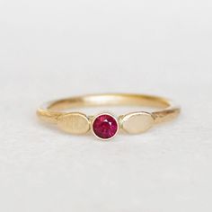 Lovely red ruby and gold petal ring. Two handmade petals frame the 3mm ruby. I gave the 1.6mm yellow gold band a hammered texture and a brushed satin finish. Sweet and elegant. Ruby - 3mm's, heat-treated Band - 1.6mm, hammered Gold - Recycled, eco-friendly - choose between 14k and 18k Finish - Comes with a brushed satin finish (pictured), unless you specify that you want a high polished finish . **Choose between 14k gold and 18k gold when you check out. Thanks for looking! Lilian Dainty Ruby Ring As Birthstone, Red Ruby Ring In 14k Gold With Bezel Setting, Hand Forged Ruby Ring In Red, Hand Forged Red Ruby Ring, Ruby Birthstone Ring In Yellow Gold, Yellow Gold Ruby Birthstone Ring With Bezel Setting, Elegant Hand Forged Yellow Gold Ruby Ring, Yellow Gold Ruby Ring With Lab-created Birthstone, Anniversary Ruby Rings Hand Forged