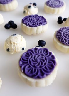 purple and white desserts with blueberries on them sitting on a counter top next to each other