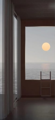 the sun is setting over the ocean from an empty room with large windows that look out onto the water