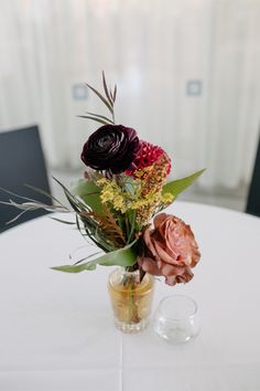 a vase filled with flowers sitting on top of a white table covered in greenery