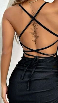 the back of a woman's dress with tattoos on her upper and lower back