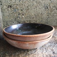 three black and brown bowls sitting on top of a granite counter next to each other