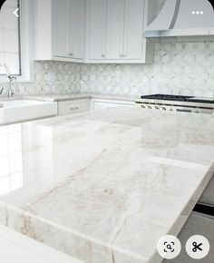 a white kitchen with marble counter tops and cabinets