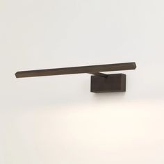 a wall mounted light on the side of a white wall with a wooden beam attached to it