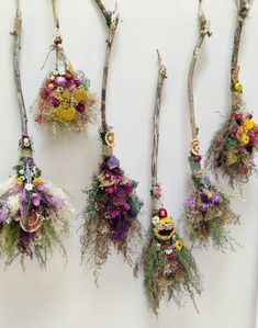 four different types of flowers hanging from branches on the wall, one is purple and yellow