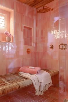 a pink tiled bathroom with a wooden bench