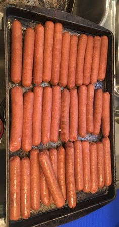 several rows of hot dogs in a pan on the stove top, ready to be cooked