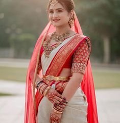 a woman in a red and white bridal outfit with her hands on her hips