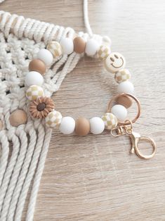 a white and brown beaded bracelet with a gold metal charm on a wooden table