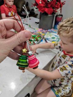 a child is playing with christmas ornaments in the kitchen while an adult holds on to them