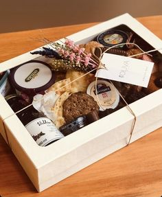 a box filled with assorted food items on top of a wooden table next to a bottle of wine