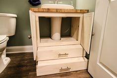 a bathroom with a sink, toilet and cabinet in it's corner next to a door