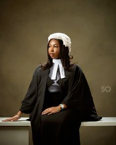 a woman sitting on a bench wearing a black robe and white bonnet with her hands in her pockets