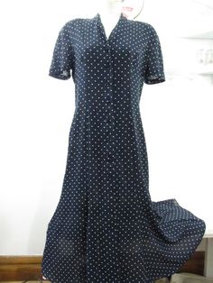 Navy blue shirtwaist dress with a button down front. Easy to wear style can be worn as a duster since it unbuttons all the way down Condition: Good. Fabric is all intact with no fading or scratching of the printed-on design. Seams and hem intact. 100% Polyester with good drape. Rough but not scratchy. Easy care, very washable and quick dry. Slip underneath recommended due to the type of fabric it is Size: 12 Bust: 20" across Length 51" ♥ All measurements are taken in inches. Please ensure fit be Formal Short Sleeve Shirt Dress With Button Cuffs, Polka Dot Short Sleeve Formal Dress, Formal Short Sleeve Polka Dot Dress, Polka Dot Collared Dress With Buttons, Collared Polka Dot Dresses With Buttons, Casual Polka Dot Button-up Dress, Polka Dot Button-up Dress, Classic Blue Shirt Dress With Buttons, Polka Dot Button-up Dress With Buttons