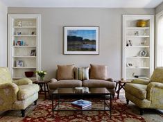 a living room with two couches, chairs and a coffee table in front of bookshelves