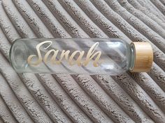 a glass bottle with the word sand on it and a wooden cap sitting on a towel