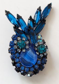 "This is a verified  Delizza and Elster Juliana brooch made of japanned  metal and set with a variety of rhinestones in shades of Bermuda blue, teal and aurora borealis and a large blue marbleized stone. This brooch can be found on page 60 of The Art of Juliana Jewelry by Katerina Musetti and on the Is It Juliana Jewelry website reference number 7280. This measures 2 1/4\" x 1  1/2\". This is a collectible piece of Juliana jewelry. There are no flaws found. We sell sparkling vintage jewelry. We like to combine shipping costs when we can, especially on jewelry. We do take close ups on all of our items and make note of any possible flaw because we believe the informed customer is the happiest customer and we want our customers to be happy. Please feel free to ask questions. No returns on vin Blue Crystal Brooch Jewelry, Blue Crystal Jewelry Brooch, Costume Jewelry Blue Brooches With Rhinestones, Blue Crystal Jewelry With Brooch Detail, Unique Blue Brooches For Formal Occasions, Unique Blue Brooch For Party, Unique Blue Brooches For Party, Juliana Jewelry, Rhinestone Statement Necklace