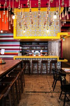 the interior of a restaurant with wooden tables and chairs, hanging lights and colorful walls