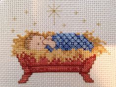 a cross stitch picture of a baby jesus in a manger