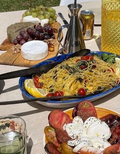 a table topped with plates of food next to bottles of wine and glasses filled with water